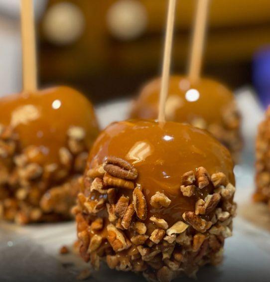Gourmet caramel candy apples with crunchy pecan coating on sticks.