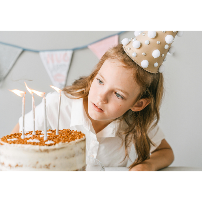 Young girl wearing a birthday party hat about to blow out candles on a birthday cake, symbolizing group birthday gifting and collaborative celebrations with family, friends, or colleagues