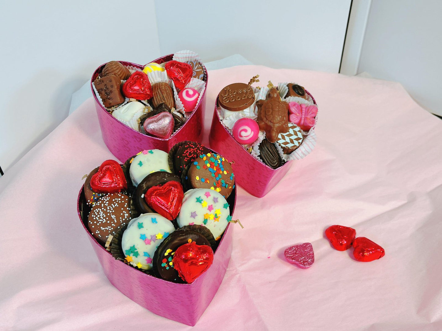 Assorted chocolate and truffle-filled 3-tier heart-shaped gift boxes in pink, designed for festive and romantic gift-giving occasions.