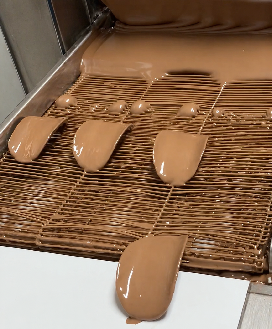 Chocolate being poured onto a wire rack with a smooth finish.