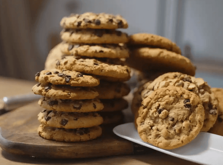 Stacks of cookies on a wooden plate and white plate with a blurred background