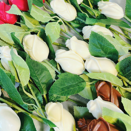Assorted chocolate roses in red, white, and milk chocolate colors arranged on a tray, ideal for party favors or Valentine's Day gifts.