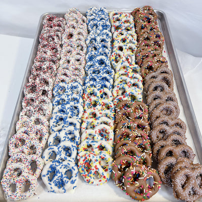 Chocolate Dipped Pretzels in assorted flavors with colorful sprinkles on a tray. Sweet and salty snack perfect for gifting or parties.