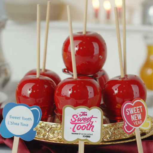 Candy apples on sticks with 'The Sweet Tooth' branding on a decorative stand.