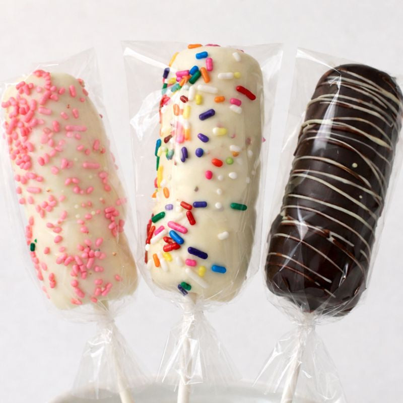 Three marshmallow pops with different toppings on a white background