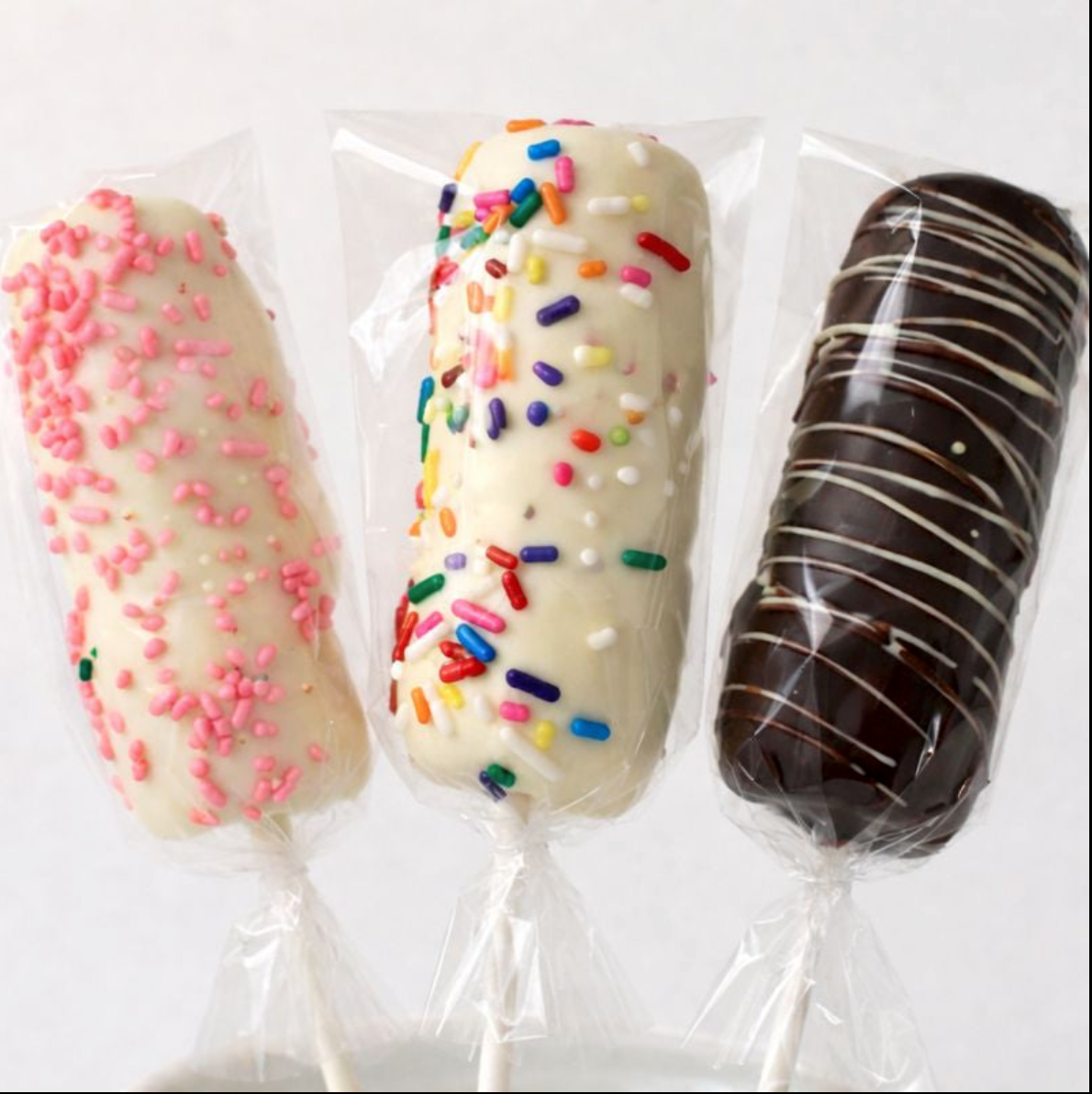 Three chocolate dipped marshmallow sticks - pink sprinkle, rainbow sprinkle, and dark chocolate drizzle