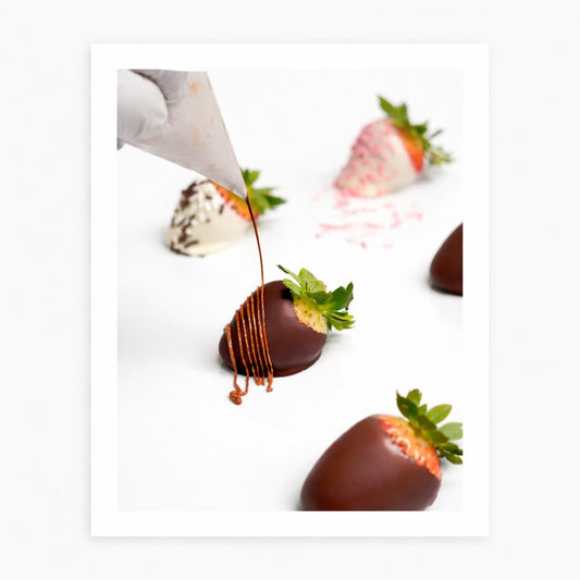 Hand-dipping a chocolate-covered strawberry in tempered chocolate at The Sweet Tooth's North Miami Beach factory