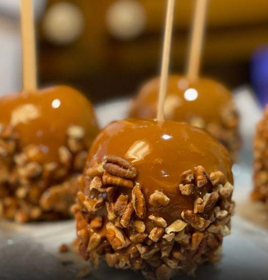 Gourmet caramel candy apples with crunchy pecan coating on sticks.