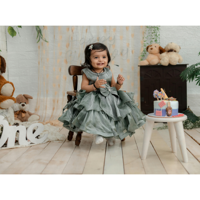 Smiling toddler girl in a fancy dress celebrating her first birthday with a themed cake and stuffed animals, illustrating age-specific birthday chocolate gift ideas for kids.