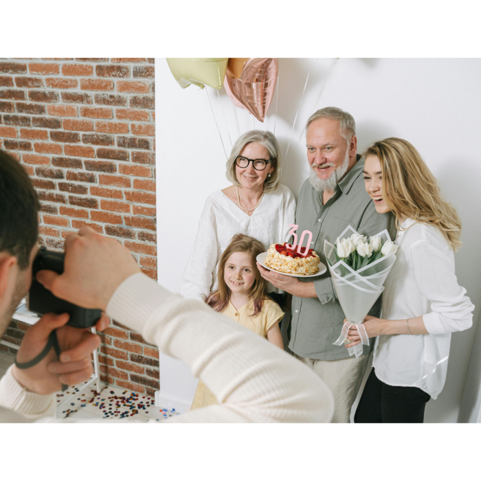 Family celebrating a milestone birthday with cake, balloons, and flowers, posing for a quick photo, representing the joy and convenience of last-minute birthday gift solutions with same-day and rush delivery.