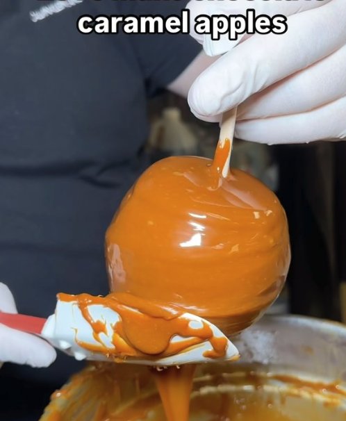 Hand-dipping a fresh apple in warm caramel for Rosh Hashanah gifts at The Sweet Tooth in North Miami Beach