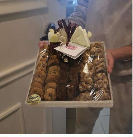 Wrapped wooden tray of cookies, brownies, and pastries delivered to a front door by The Sweet Tooth