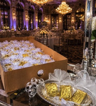 Gold chocolate bar wedding favors in tulle wrap from The Sweet Tooth staged in an elegant ballroom