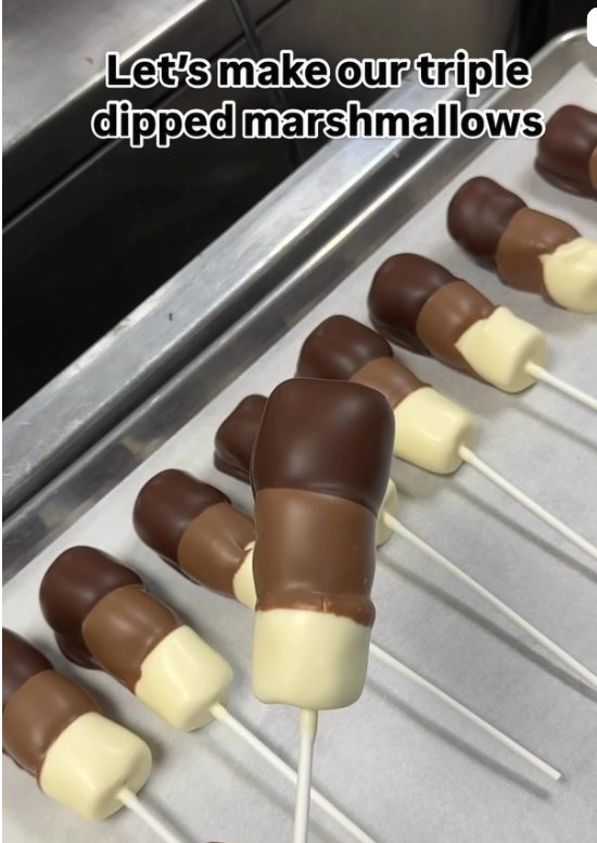 Rows of triple-dipped marshmallow pops layered in dark, milk, and white chocolate on a lined tray