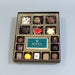 Box of assorted chocolates with a Rolex logo on a wooden surface