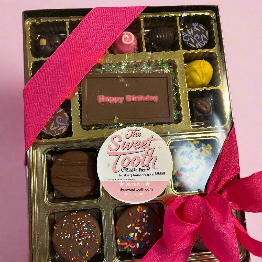 Birthday chocolate gift box by The Sweet Tooth featuring assorted handcrafted chocolates and a 'Happy Birthday' chocolate bar, wrapped with a pink ribbon.