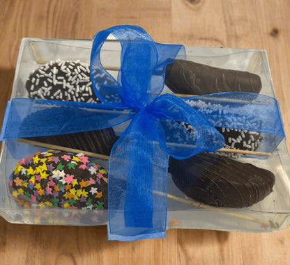 Chocolate Dipped  Apple Sticks 6-pack in clear gift box with blue ribbon, featuring assorted toppings like sprinkles and chocolate drizzle.