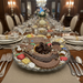 Dining table set with a large chocolate Sweet  Tooth centerpiece, surrounded by plates, glasses, and silverware.