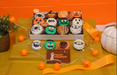 12-pack of Halloween-themed chocolate-dipped Oreos from The Sweet Tooth, featuring spooky designs like mummies, pumpkins, and monsters, beautifully arranged in a festive box