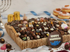 Assorted chocolates in a basket with a 'Happy Hanukkah' chocolate plaquesurrounded by festive decor on a table.