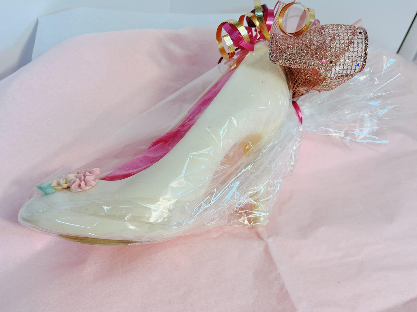 White chocolate high heel wrapped in cellophane with pink and gold ribbons, perfect for elegant chocolate gift presentations.