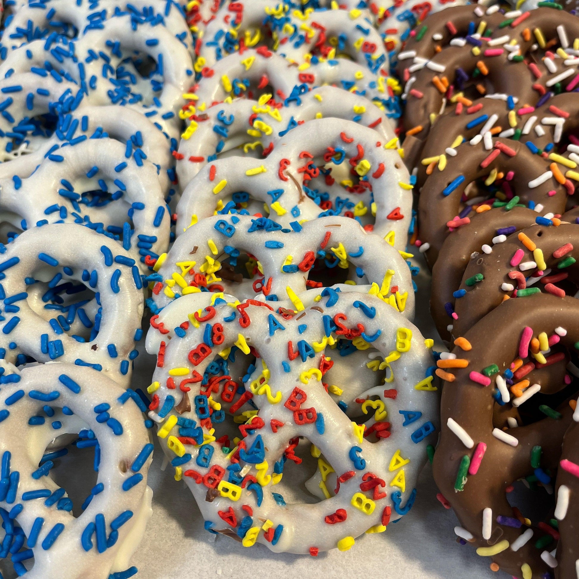 Close-up of Chocolate Dipped Pretzels with blue, red, and yellow sprinkles. A festive sweet and salty snack for all occasions.