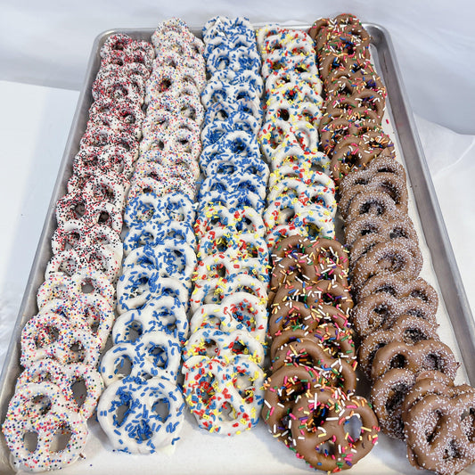 Chocolate Dipped Pretzels in assorted flavors with colorful sprinkles on a tray. Sweet and salty snack perfect for gifting or parties.