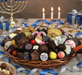 Assorted chocolates in a basket with Hanukkah decorations including a menorah and candles.