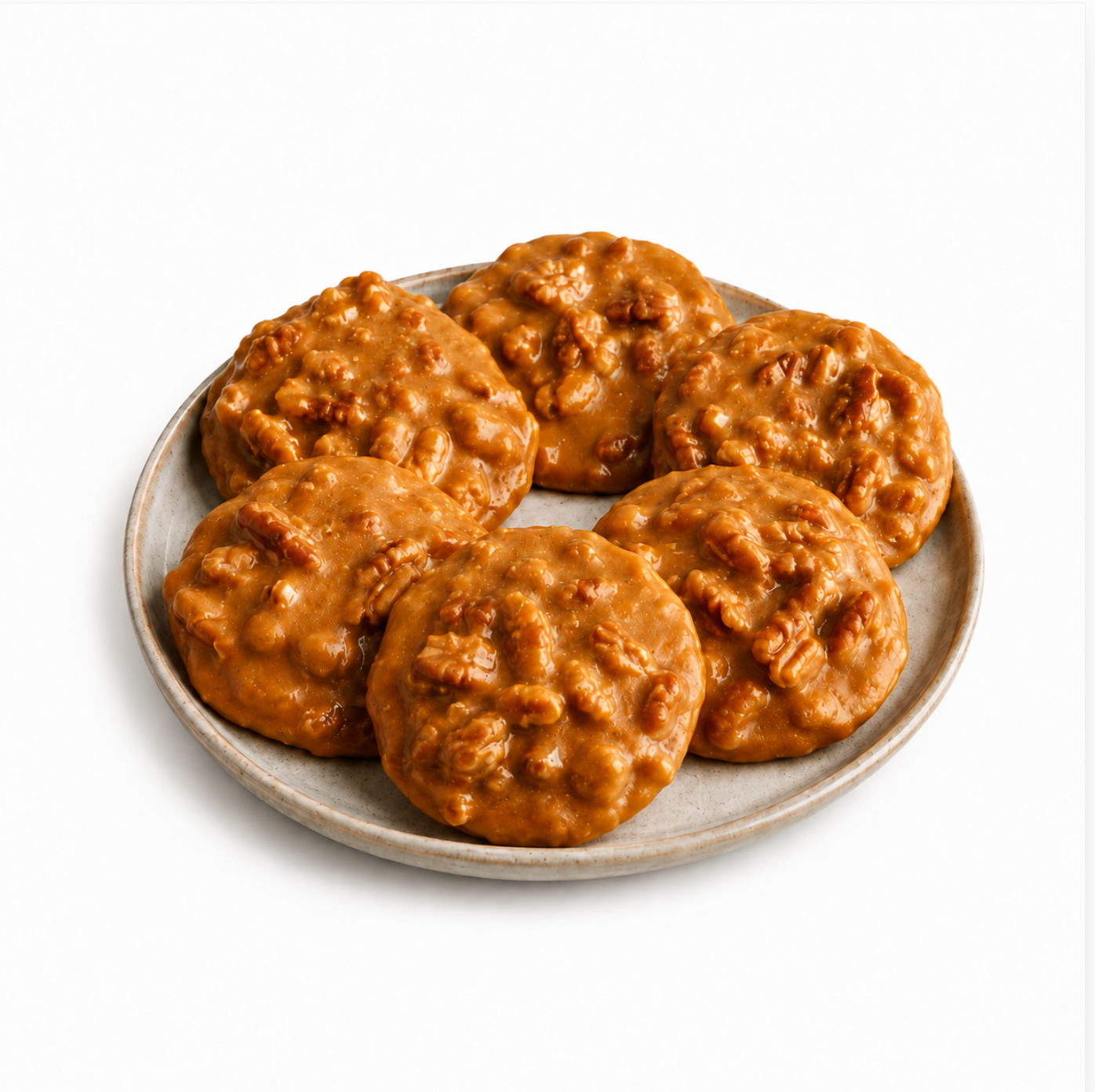Six golden-brown caramel and pecan pralines arranged on a round gray ceramic plate against a clean white background.