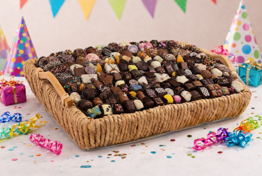 Basket of assorted chocolates on a festive table with colorful decorations.