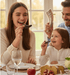 Family of three enjoying a meal together with a focus on a woman and child holding small decorative items.