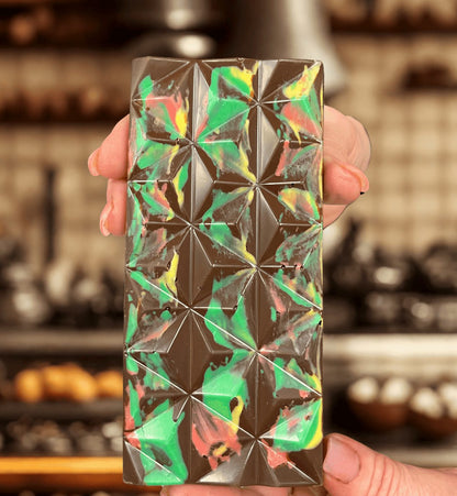 Hand holding a Passover Dubai Chocolate Bar with colorful marbled top and geometric pattern, emphasizing its artisanal design.