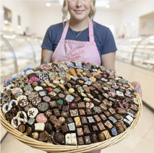 Person holding a large 30inch chocolate 400 pieces basket of assorted chocolates in a store setting for birthday and teachers appreciation