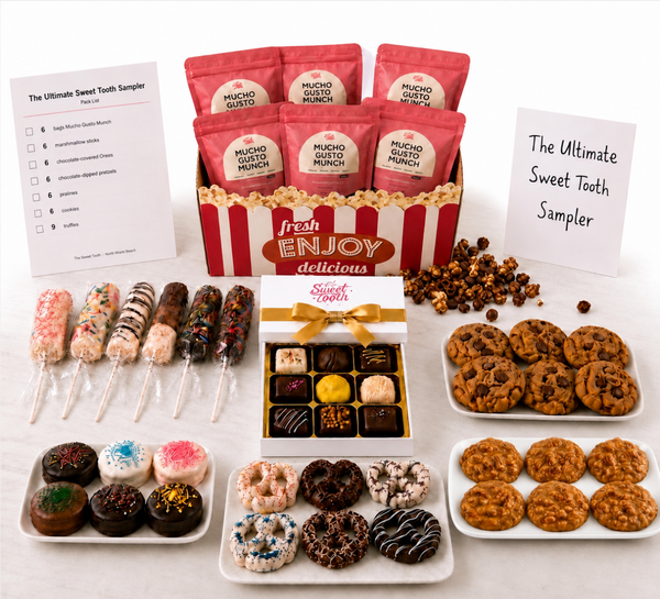 A tooth sampler gift set arranged on a white surface, featuring red pouches of Mucho Gusto sugar-free gum in a striped gift box, assorted chocolate-covered popsicles, a box of assorted chocolates, cookies, donuts, and popcorn, with two sample checklists and handwritten notes reading 'The Ultimate Sweet Tooth Sampler'.