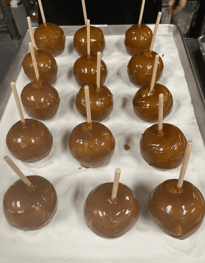 Caramel apples with sticks on a baking sheet