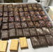 Tray of chocolate-covered cookies with various toppings on a metal surface.