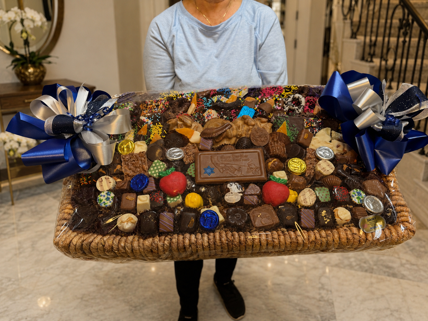 Customer holding a Jumbo rectangle chocolate gift basket wrapped in cellophane with hand-tied bows